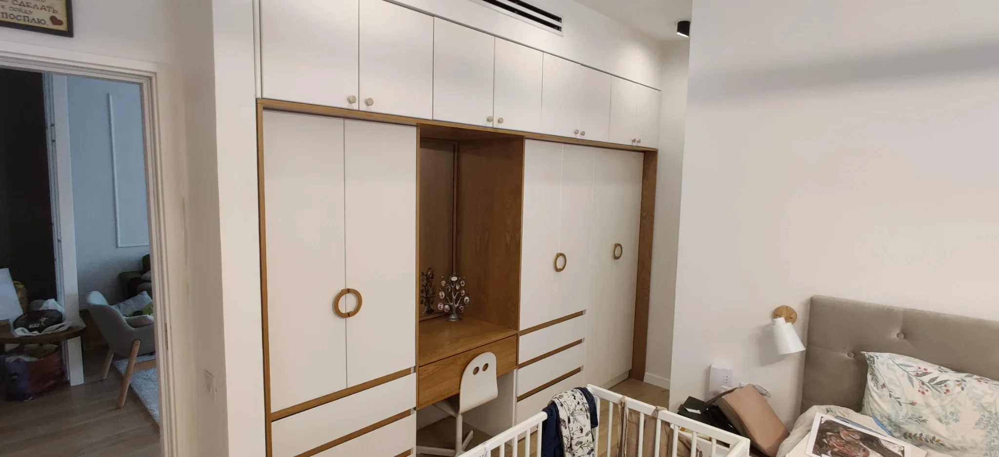 ארון קיר בלבן ואלון עם ידיות עץ מוצמדות בצורת טבעת, סביב גומחת שולחן פתוחה